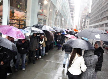  미국 소비자들이 뉴욕 애비뉴 5번가에 위치한 애플 매장에서 아이패드 2를 구매하기 위해 우산을 받치면서까지 장사진을 지난 16일 이루고 있다.<뉴욕(미국)=로이터 연합뉴스>  