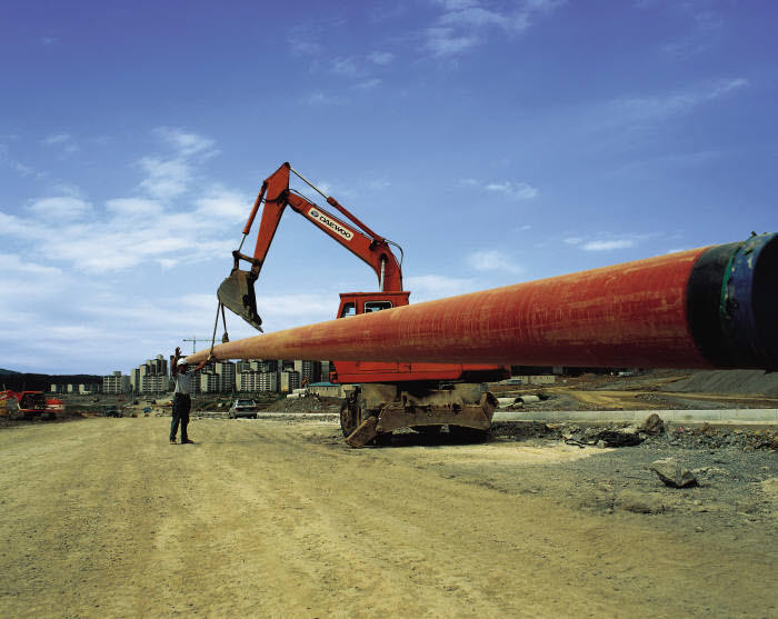 대형 포크레인으로 도시가스 배관을 땅에 묻고 있다.