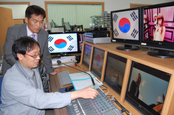 이기원 사장(서있는 사람)과 연구원이 디지털기반 학교방송시스템에 대해 이야기를 나누고 있다.