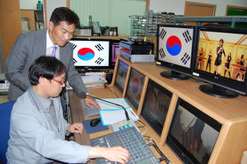 이기원 사장(서있는 사람)과 연구원이 디지털기반 학교방송시스템에 대해 이야기를 나누고 있다.