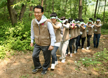 남상건 LG상록재단 부사장(맨 왼쪽)이 숲 교실에 참가한 학생들과 함께 직접 숲을 체험해보는 프로그램인 `애벌레 놀이`를 하고 있다. 애벌레 놀이는 눈 없이도 몸의 감각만으로 이동하는 애벌레처럼 눈을 감고 기차놀이를 하며 자연과 교감해보는 프로그램이다.
 