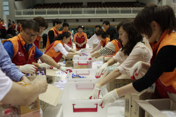 SK그룹 임직원 등 자원봉사자 170여명이 29일 서울 강남구 일원동 밀알학교 체육관에서 열린 풍수해 이재민 지원용 `긴급구호 킷(Kit)` 제작행사에 참가해 구호 킷을 만들고 있다. SK는 향후 폭우, 폭설, 태풍 등 재해 발생시 이날 제작한 구호 킷 2000여개를 활용해 이재민 구호활동을 펼칠 예정이다.