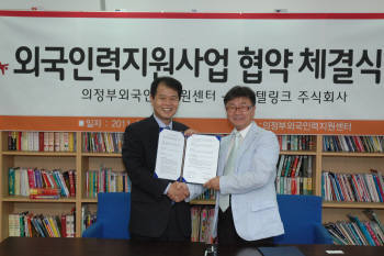 홍성균 SK텔링크 마케팅본부장(왼쪽)과 이광일 외국인인력지원센터 소장이 MOU를 교환한 후 악수하고 있다.