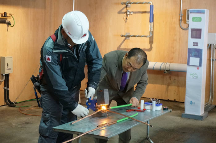 최돈학 학산전력 사장(오른쪽)이 직원과 함께 전기설비 시공표준으로 제안한 기술을 시연해 보이고 있다.