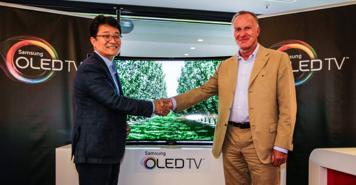 삼성전자가 유럽에 OLED TV를 출시한다. 사진은 이달 24일 독일 프로축구 구단인 FC바이에른 뮌헨의 홈구장 뮌헨 알리안츠 아레나에서 김동민 삼성전자 독일 법인장(상무, 왼쪽)이 곡면 OLED TV 유럽 1호 고객인 FC바이에른 뮌헨 칼 하인츠 루메니게 CEO에게 제품을 전달하고 있다.