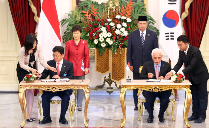 윤상직 산업통상부 장관이 12일 오후 인도네시아 자카르타 대통령궁에서 박근혜 대통령과 수실로 밤방 유도유노 대통령이 배석한 가운데 히다얏 산업장관과 경제특구 개발협력 MOU에 서명하고 있다. <연합뉴스>