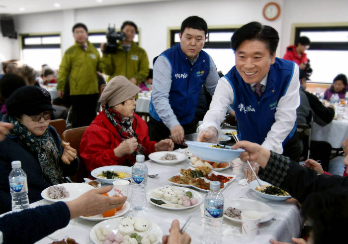 유정석 현대HCN 대표가 설맞이 사랑 나눔 행사에서 어르신께 떡국을 전달하고있다.