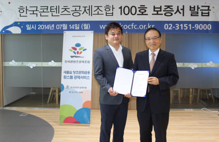 한국콘텐츠공제조합(은 시너지미디어에 100번째 보증서를 14일 상암동 조합사무실에서 발급했다. 이염 콘텐공제조합 전무(오른쪽)가 강유신 시너지미디어 대표에 보증서를 전달했다.