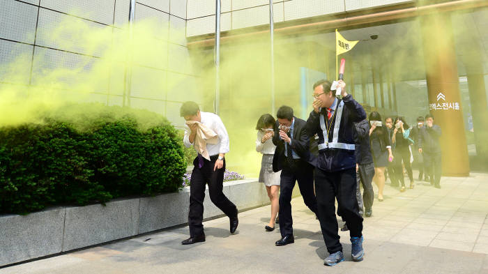 한국무역협회와 코엑스는 지난 5월 서울 삼성동 트레이드타워와 아셈타워 등 무역센터 고층건물의 재난발생시 신속히 대응할 수 있는 ‘고층건물 화재발생 대피훈련’을 실시했다. 입주자들이 손수건으로 코와 입을 가리고 건물 외부로 대피하고 있다.