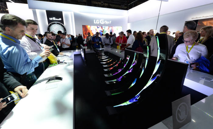 LG전자가 ‘CES 2015’에서 전작보다 크기는 줄이고 해상도를 높인 5.5인치 풀HD 플라스틱 OLED(P-OLED)디스플레이를 적용한 `G플렉스2`를 전시했다. LG전자 전시장을 방문한 관람객들이 G플렉스2를 체험해 보고 있다.