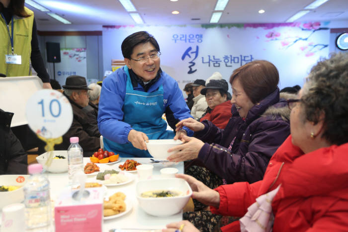 12일 설 명절을 앞두고 서울 중구 유락종합사회복지관에서 열린 ‘어르신 초청 설 나눔 한마당 잔치’ 에서 이광구 우리은행장(사진 가운데)이 떡국 배식을 하고 있다.