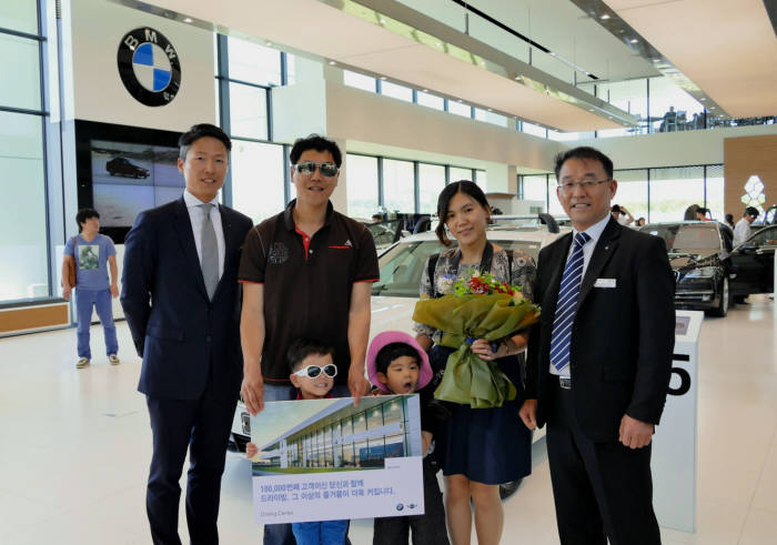 장성택 BMW 드라이빙센터장(맨 오른쪽)이 10만번째 방문객 홍혜란·홍우기씨 가족에게 화환을 전달한 후 기념촬영했다.