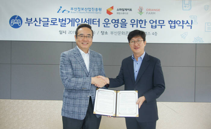 서태건 부산정보산업진흥원장(왼쪽)과 양동기 스마일게이트엔터테인먼트 사장이 BGC 운영 협약 후 악수하고 있다.