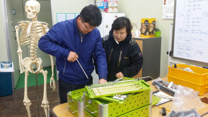 이경구 광주테크노파크 생체의료부품센터장(왼쪽)과 김선미 티디엠대표가 타이타늄소재의 의료부품의 강도를 테스트하고 있다.