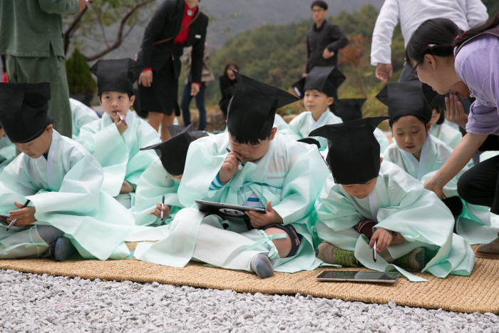 청학동 서당 어린이들이 도포와 유건을 착용하고 태블릿PC와 애플리케이션으로 과거시험을 치르고 있다.