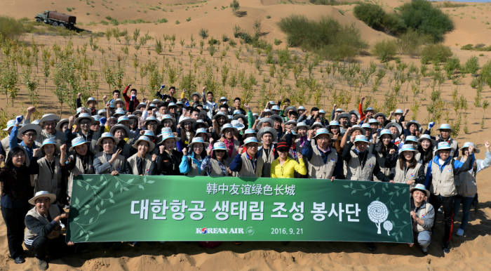 중국 네이멍구(內蒙古) 쿠부치 사막에서 나무심기 봉사활동에 참가한 대한항공 직원들과 중국 대학생들이 기념 촬영을 하고 있는 모습 (제공=대한항공)