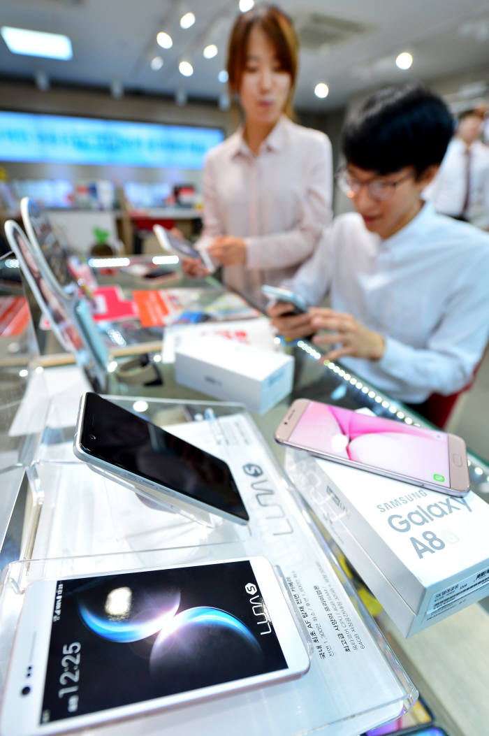이동통신사 전용폰이 큰 호응을 얻고 있다. 17일 서울 명동 SK텔레콤 매장을 찾은 고객이 전용폰 `TG앤컴퍼니 루나S`와 `삼성전자 A8` 모델을 살펴보고 있다. 윤성혁기자 shyoon@etnews.com