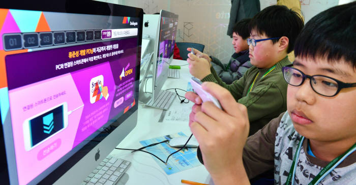 2015년, 경기도 분당 종합 직업체험관 `한국잡월드`를 찾은 학생들이 직접 프로그래밍한 게임을 스마트폰으로 전송해 시연해보고 있다.