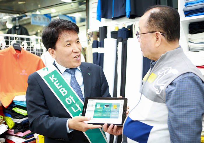 함영주 KEB하나은행장(왼쪽)이 태블릿브랜치를 이용해 동대문종합상가 입점 상인에게 금융거래 상담을 진행하고 있다