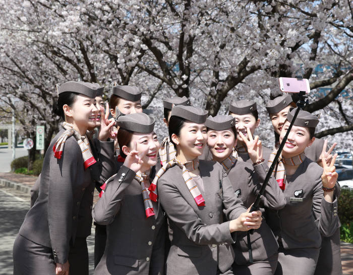 12일 서울 오쇠동 아시아나항공 본사에서 만개한 벚꽃 아래 캐빈 승무원들이 기념 사진을 찍고 있다. (제공=아시아나항공)