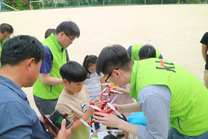 드론 동호회에서 어린이에게 드론 조정방법을 설명해주는 모습