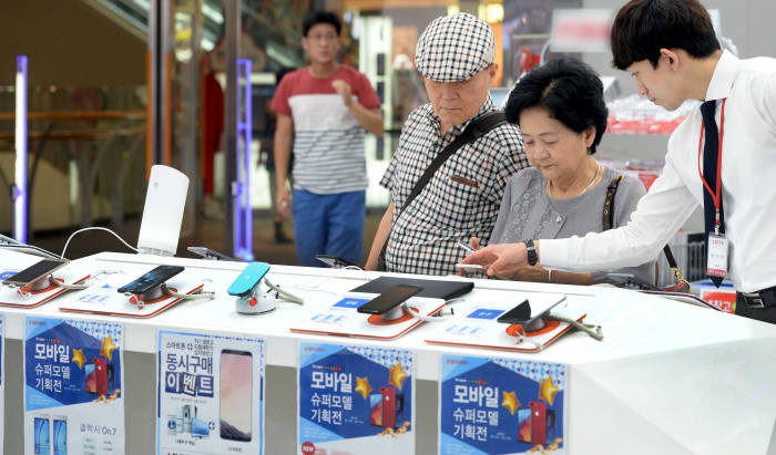 롯데하이마트 모바일 매장에서 고객들이 스마트폰을 살펴보고 있다. <전자신문 DB>