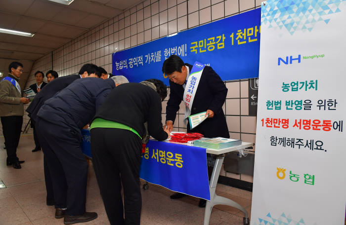 농협은행 경영기획부문 직원들이 농협은행 본점 앞과 지하철 역사에서 시민 대상으로 농업가치 헌법반영 안내장을 배부하고 서명운동 동참을 설명하고 있다.