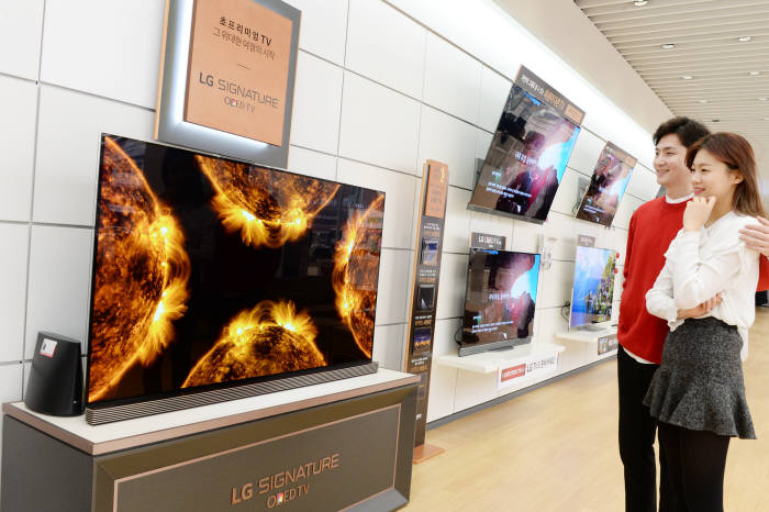LG전자 모델들이 가전 매장에서 'LG 올레드 TV'를 살펴보고 있다. <자료 LG전자>