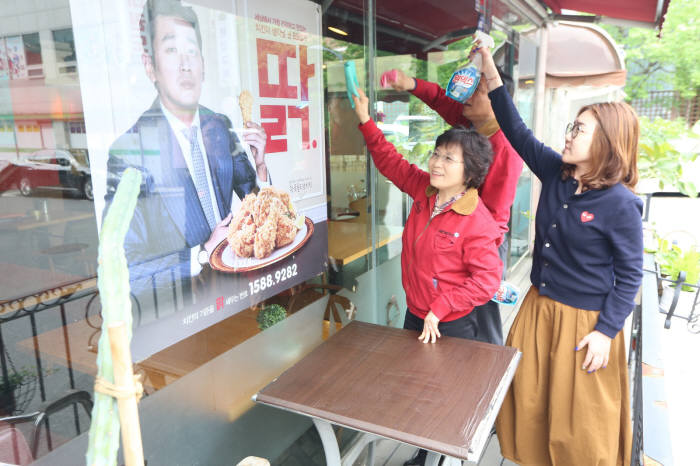 윤경주 BBQ 사장(사진 왼쪽) 및 임직원들이 매장 청결 활동을 하고 있다.