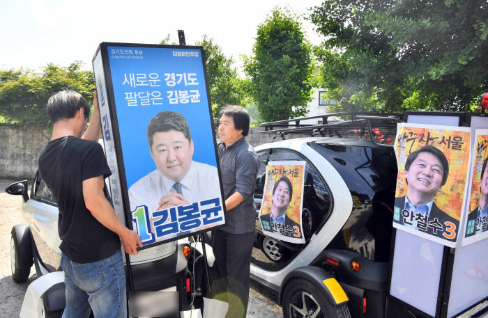 6·13 지방선거 공식 선거운동 전날인 30일 전기차 트위지에 홍보용 설치물과 포스터를 붙이는 작업이 진행되고 있다. 수원=박지호기자 jihopress@etnews.com