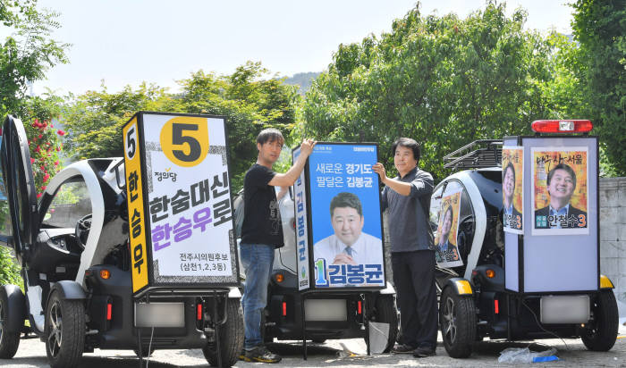 6·13 지방선거 공식 선거운동 전날인 30일 전기차 트위지에 홍보용 설치물과 포스터를 붙이는 작업이 진행되고 있다. 수원=박지호기자 jihopress@etnews.com