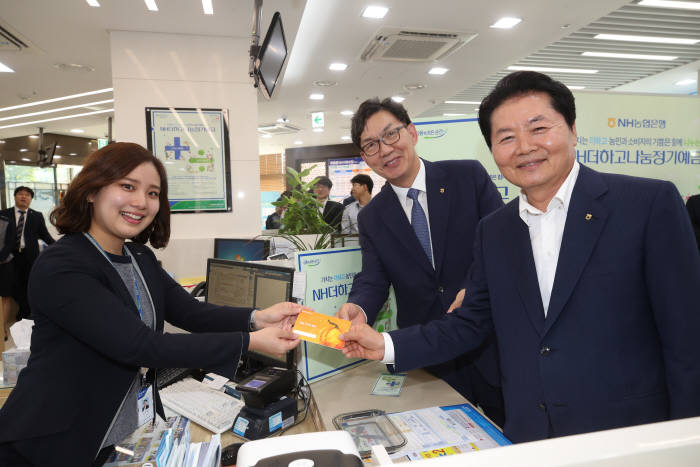 김병원 농협중앙회장이 27일 본점 영업부를 방문하여 1호 고객으로 상품에 가입 후 이대훈 NH농협은행장, 영업점직원과 함께 기념촬영을 하고 있다. (왼쪽부터 김부경 계장, 이대훈농협은행장, 김병원 농협중앙회장)