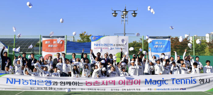 매직테니스 행사에 참가한 어린이들과 강사진, 송하진 전북도지사(맨 뒷줄 왼쪽부터 열두번째), 이대훈 농협은행장(맨 뒷줄 왼쪽부터 열한번째), 김장근 농협은행 전북 영업본부장(맨 뒷줄 왼쪽부터 열번째)이 모자를 하늘 높이 날리며 기념사진을 촬영하고 있다.