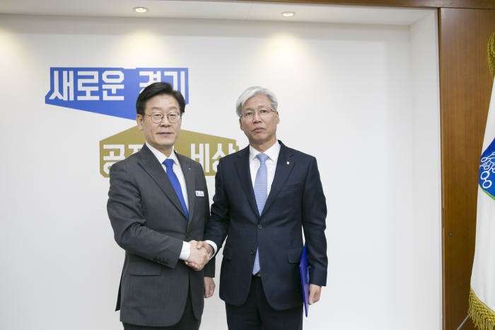이민우 경기신보 이사장(오른쪽)이 이재명 지사에게 임명장을 받고 악수하고 있다.