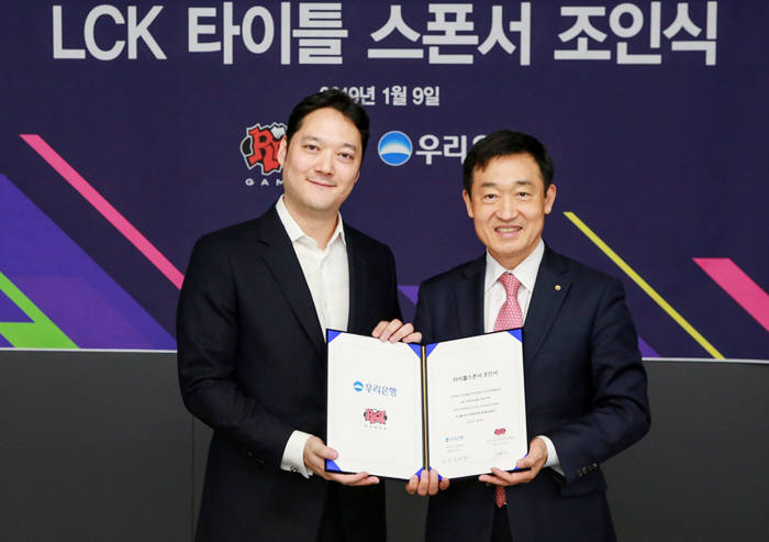 우리은행이 지난 9일 서울시 종로구 그랑서울 롤 파크에서 라이엇 게임즈와 e스포츠 리그 오브 레전드 챔피언스 코리아(LCK) 타이틀 스폰서 조인식을 가졌다. 정채봉 우리은행 부문장(오른쪽)과 박준규 라이엇 게임즈 한국대표가 기념 촬영했다.