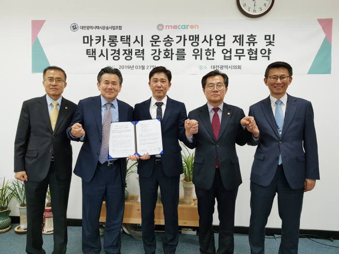 이행열 KST모빌리티 대표(사진 가운데)와 김성태 대전시택시운송사업조합 이사장(사진 왼쪽에서 두번째)가 지난 27일 대전시의회에서 혁신형 택시 브랜드 마카롱택시 도입을 위한 업무협약을 체결한 뒤 이종호 대전시의원, 이광복 대전시의원, 박제화 대전시 교통건설국장과 기념촬영하고 있다. 사진출처=KST모빌리티