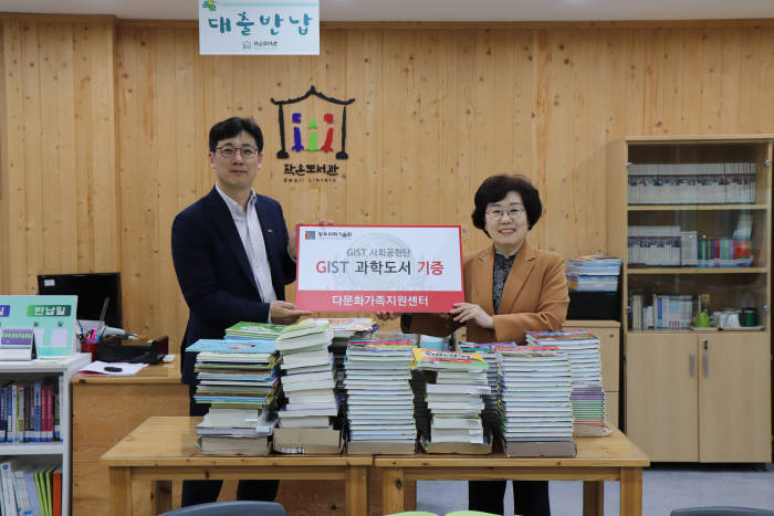 박성규 GIST 사회공헌단장(왼쪽)이 26일 문미선 광주 북구 다문화가족지원센터장에게 과학도서를 전달하고 있다.