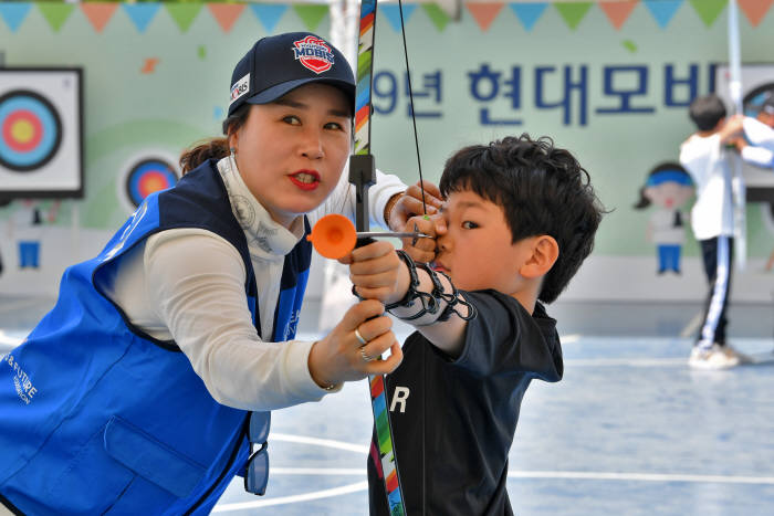 5월 5일 어린이날을 맞아 천안 종합운동장에서 열린 현대모비스 어린이 양궁교실에 참여한 아이들이 전직 국가대표 금메달리스티인 주현정 선수의 도움을 받아 활시위를 당기고 있다. (제공=현대모비스)