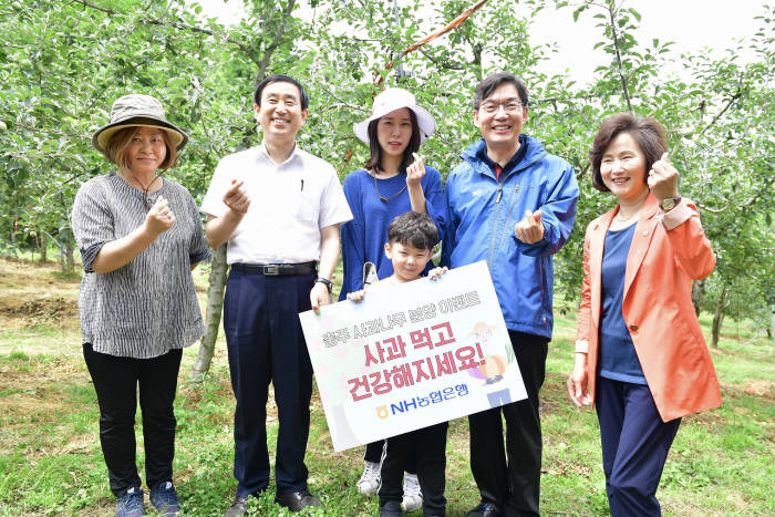 이대훈 농협은행장(오른쪽 두번째), 조길형 충주시장(왼쪽 두 번째), 허영옥 충주시의장(오른쪽 첫 번째)이 고객과 함께 사과나무 앞에서 기념촬영했다.