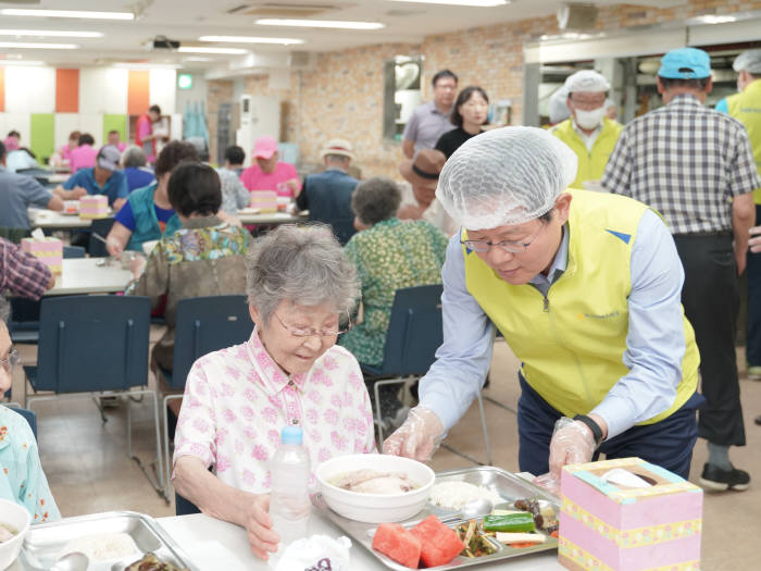 김광수 농협금융 회장(오른쪽)이 서울 중구 소재 신당데이케어센터를 방문해 관내 어르신에게 삼계탕을 대접하고 있다.