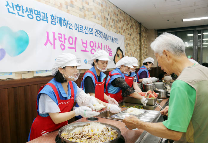 신한생명 직원봉사자들이 지난 20일 서울 양천어르신종합복지관에서 어르신에게 보양식 배식을 하고 있다.