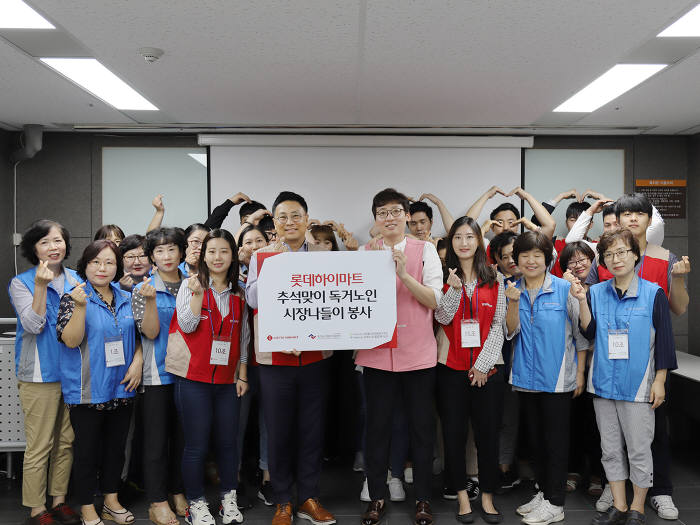 진철호 롯데하이마트 강북지사장(앞줄 왼쪽 다섯번째)과 나영식 강북노인종합복지관 부장(앞줄 왼쪽 여섯번째), 롯데하이마트 샤롯데봉사단원들이 하트를 그려보이고 있다.