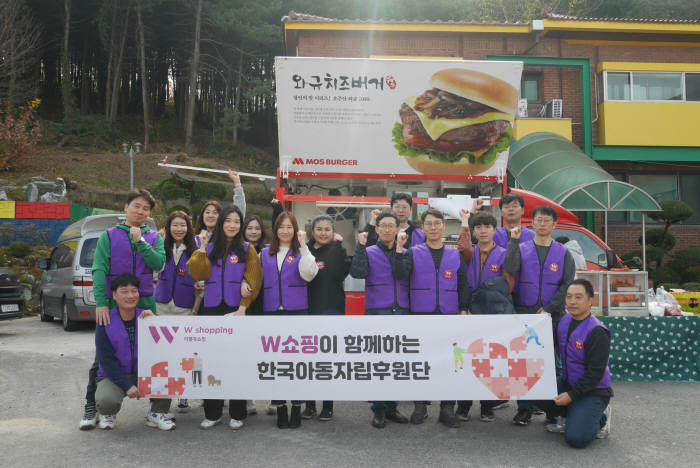 W쇼핑 임직원들이 지난 23일 서울 SOS어린이마을에서 사회공헌활동을 펼친 뒤 한자리에 모여 서울 SOS마을 관계자들과 함께 기념촬영했다.