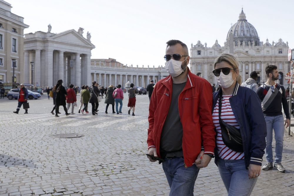 FILE - In this Thursday, Feb. 27, 2020 file photo, a couple wearing face masks stroll outside St. Peters Square, at the Vatican. A U.S. government advisory urging Americans to reconsider travel to Italy is the final blow to the nations tourism industry due to a new virus, the head of Italys hotel federation said Saturday, Feb. 29, 2020. (AP Photo/Gregorio Borgia, file)