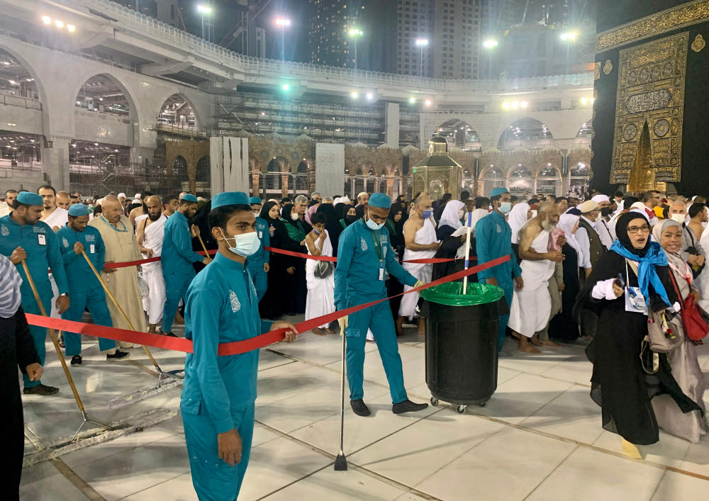 Sanitary workers wearing protective face masks continue to clean the sahn (mosque courtyard) surrounding the Kaaba, Islams holiest shrine, as Muslim worshippers pray at the Grand Mosque complex in Saudi Arabias holy city of Mecca on February 27, 2020. - Saudi Arabia on February 27 suspended visas for visits to Islams holiest sites for the "umrah" pilgrimage, an unprecedented move triggered by coronavirus fears that raises questions over the annual hajj. The kingdom, which hosts millions of pilgrims every year in the cities of Mecca and Medina, also suspended visas for tourists from countries affected by the virus as fears of a pandemic deepen. (Photo by Haitham EL-TABEI / AFP)