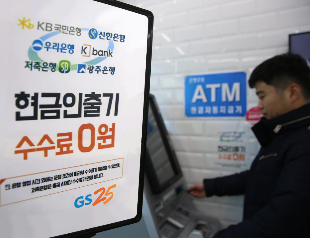 GS25에서 고객이 ATM 서비스를 이용하고있다.