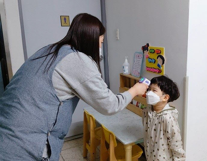 한 어린이집에서 비접촉식 체온계로 체온을 측정하고 있다.