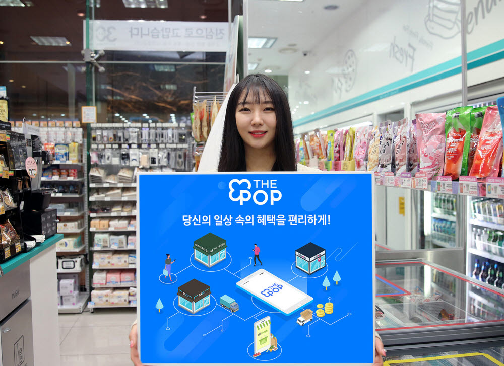 모델이 GS25 매장에서 GS리테일 통합멤버십 THE POP 출범을 기념해 홍보물을 들고있다.