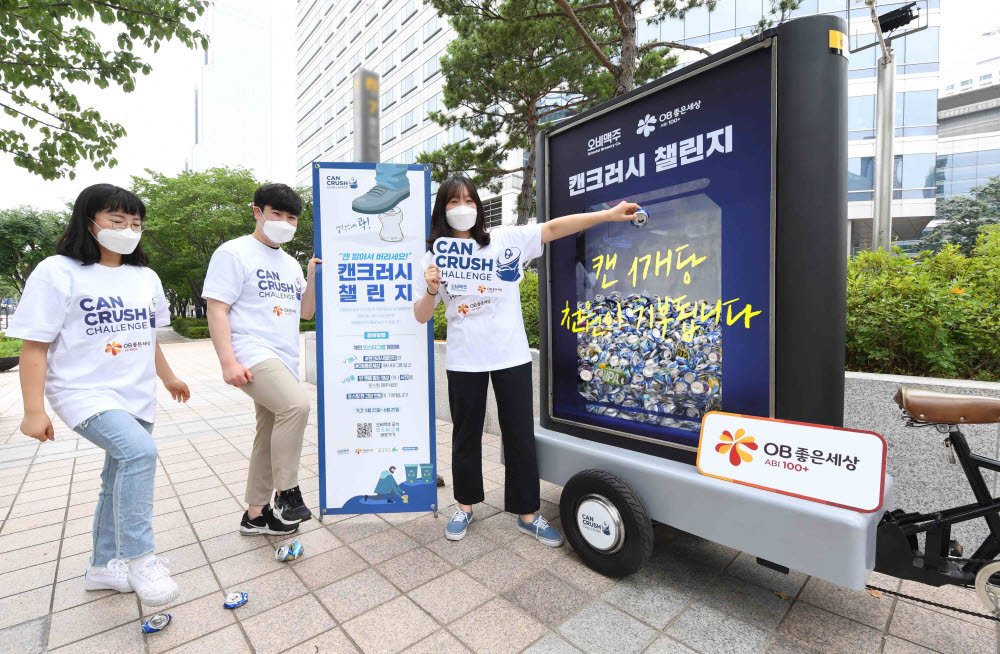 오비맥주 직원들이 강남구 삼성동 본사 앞에서 알루미늄 캔의 올바른 분리배출법을 알리는 캔크러시 챌린지 캠페인에 참여하고 있다.