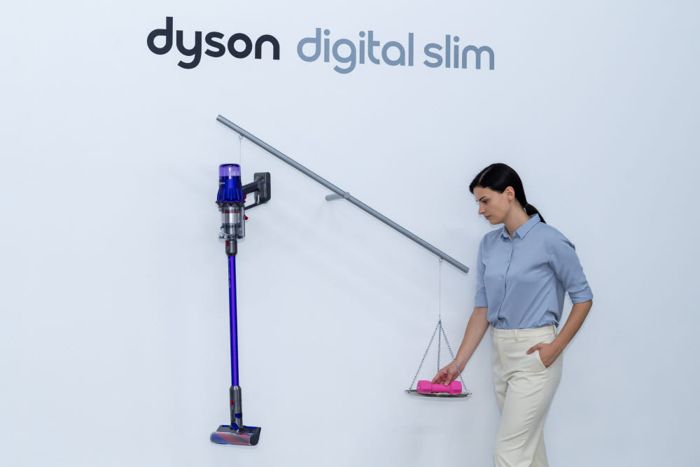 다이슨코리아 트레이너가 2kg 아령과 다이슨 디지털 슬림™ 을 저울에 올려 무게를 비교하고 있다.
